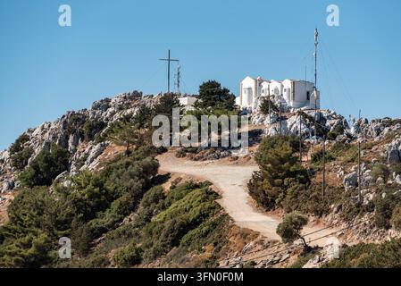 Aufnahme mit Teleobjektiv, die die weiß getünchte Afentis-Christos-Kapelle und das markante Gipfelkreuz auf dem Berg Juktas in Kreta, Griechenland, einfängt Stockfoto