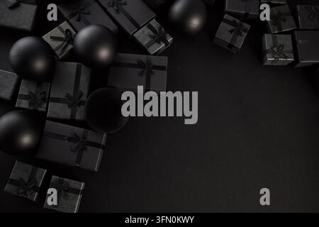 Schwarze Geschenkboxen mit Schleife und Ornamenten auf dunklem Hintergrund Stockfoto