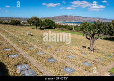 Ein malerischer Blick über die Grabstätten und drei stehende Gedenkkreuze auf dem Maleme-Kriegsfriedhof. Der friedliche Ruheplatz blickt auf das blaue Wasser Stockfoto