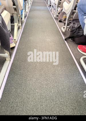 Flugzeugkabine Gang mit Passagiersitzen und Füßen – Innenansicht eines Linienflugzeugs Stockfoto