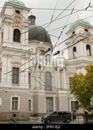 SALZBURG, ÖSTERREICH - 13. OKTOBER 2025: Die monumentale barocke Fassade und die beiden Glockentürme der Heilig-Dreifaltigkeits-Kirche erheben sich neben dem Makartplatz in Salzburg. Stockfoto