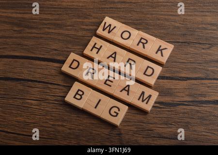 Holzbriefsteine mit der Aufschrift Work Hard Dream Big auf einem Holzgrund, symbolisch für Motivation, Ehrgeiz, Ausdauer, Erfolg, Zielsetzung Stockfoto