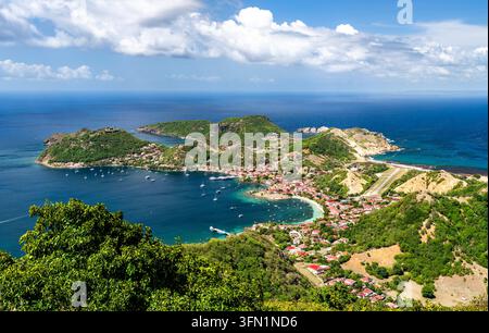 Panoramische Luftaufnahme über die Bucht, das Dorf und die grünen Hügel der Insel Terre-de-Haut in Les Saintes, Guadeloupe. Stockfoto