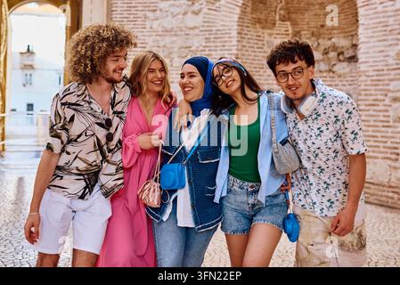 Verschiedene Gruppe junger Freunde, die lachen und zusammen durch historische Stadtstraßen im Urlaub gehen Stockfoto