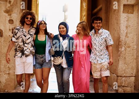 Multikulturelle Gruppe von Freunden geht gemeinsam in einer historischen Straße an einem sonnigen Sommertag Stockfoto