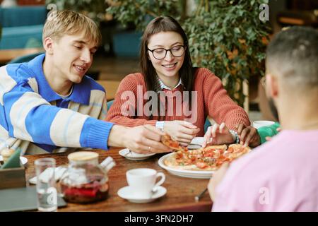 Multikulturelle Freunde teilen Pizza und essen zu Mittag im Café Stockfoto