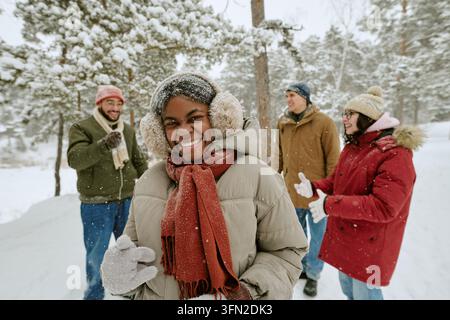 Porträt einer glücklichen schwarzen Frau mit verschiedenen Freunden in einem verschneiten Park Stockfoto