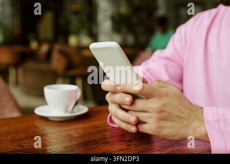 Hände eines Mannes, der ein Smartphone benutzt, während er in einem Café sitzt Stockfoto