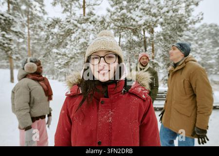 Porträt einer lächelnden Frau mit verschiedenen Freunden in einem verschneiten Winterwald Stockfoto