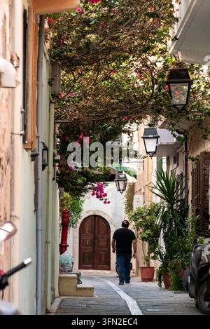 Rethymno, Griechenland – 01. Oktober 2026 – Eine friedliche Person geht eine ruhige Wohnstraße entlang, umgeben von grünen Büschen und einem großen Baum, der zu Stockfoto