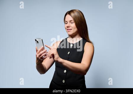 Geschäftsfrau hält ein Mobil-Smartphone und berührt den Bildschirm in einem Studiofoto Stockfoto