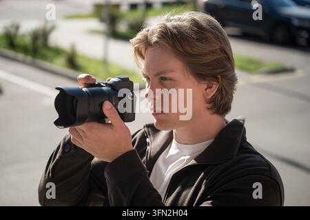 Junger Fotograf macht Fotos im Freien. Fotografentag Stockfoto