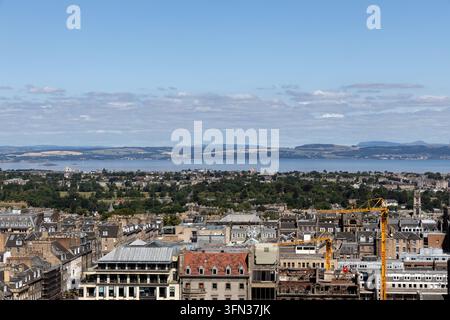 Panoramablick auf Edinburgh, Schottland, vom Edinburgh Castle, mit historischen Stadtdächern, urbaner Architektur und dem Firth of Forth Stockfoto