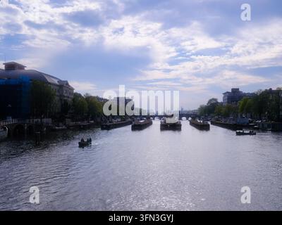 Blick nach Süden entlang der Amstel vom Magere Brug, auch bekannt als Skinny Bridge, mit Booten, Hausbooten und dem Koninklijk Theater Carré in Amsterdam, Niederlande Stockfoto