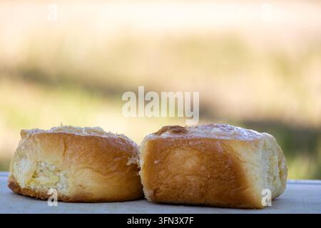 Weihnachtsglasierte Süßbrötchen auf einem weißen Schneidebrett im Freien mit weichem Bokeh-Hintergrund Stockfoto