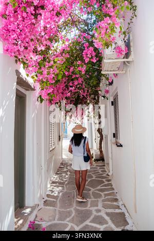 Ein ruhiger Spaziergang in Lefkes, Paros, Griechenland, offenbart malerische weiß getünchte Gebäude, die von blühenden Bougainvilleen umschlungen sind. Die hellen Blumen umrahmen den Kopfsteinpflasterweg Stockfoto