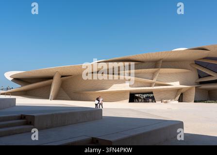 Doha, Katar - 14. Februar 2026: Weite Aufnahme des Nationalmuseums von Katar in Doha, Katar, mit Touristen auf dem sonnenbeschienenen Platz. Stockfoto