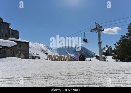 Riesige hölzerne Avoriaz-Buchstaben stehen im Schnee unter einem Sessellift, mit schroffen schneebedeckten Gipfeln Stockfoto