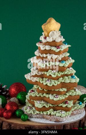 Dekorativer Weihnachtsbaum aus sternförmigen Festtagskeksen und mit festlichen Weihnachtsschmuck und Tannenzapfen dekoriert. Kreatives essbares Dekor Stockfoto