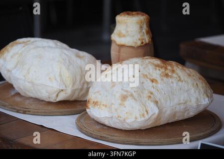 Frisch gebackenes Brot und traditionelles Geschirr auf Holztablett Stockfoto