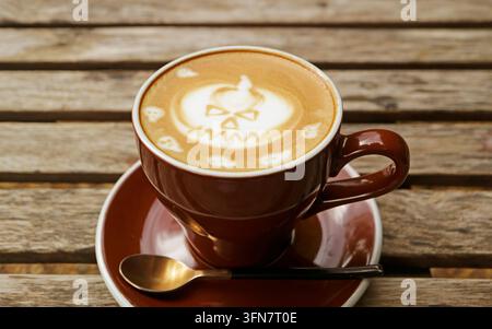 Heißer Cappuccino mit gruseligem Jack-O-Lantern-Kürbislatte-Art, warmer brauner Ton, stimmungsvoller Hintergrund Stockfoto