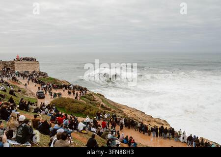 Nazare, Portugal - 6. Dezember 2025: Eine Menschenmenge beobachtet Surfer, die die Wellen bezwingen Stockfoto