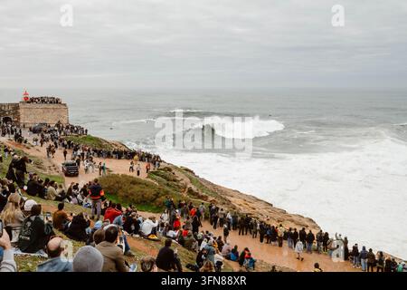 Nazare, Portugal - 6. Dezember 2025: Eine Menschenmenge beobachtet Surfer, die die Wellen bezwingen Stockfoto