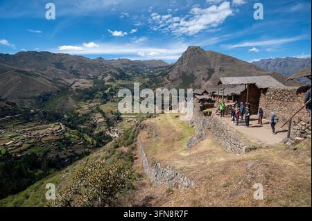 Gruppe von Touristen erkundet Inka-Ruinen und Steinterrassen auf einem Hügel mit weitläufigen Blicken auf das Andental in der Nähe von Pisac im Heiligen Tal von Cusco, Peru. Cl Stockfoto
