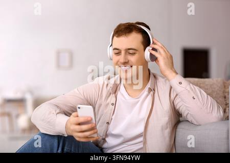 Geistesgesundheit und Entspannung, junger Mann hört Musik mit Kopfhörern und Smartphone zu Hause zur Stressbewältigung und digitalen Unterhaltungslebensstil Stockfoto