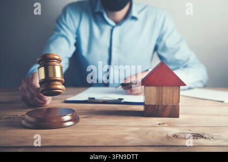 Recht und Gerechtigkeit Konzept. Männerhand mit Hammer und Hausmodell Stockfoto