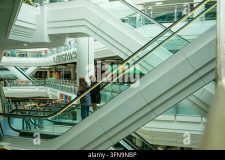 zwei junge Frauen fahren die Rolltreppen in den Galerien des Einkaufszentrums in Bristol, UK Stockfoto