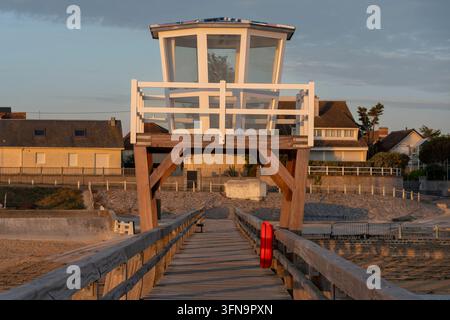 Luc-Sur-Mer, Frankreich - 08 08 2026: Blick auf den hölzernen Fischersteg, den Sandstrand, Häuser entlang des Steinstegs im Morgenlicht Stockfoto