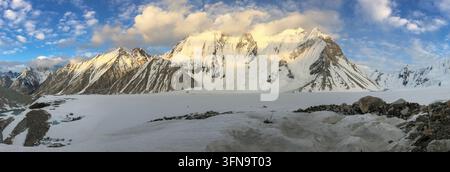 Blick auf Ali Camp K2 mit schneebedeckten Gipfeln des Karakorum-Gebirges, Gletschereis und felsigem Gelände unter einem blauen Himmel in Skardu, Gilgit, Pakistan. Stockfoto