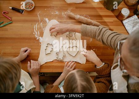 Seniorin mit Kindern, die zu Hause Feiertagsplätzchen backen Stockfoto