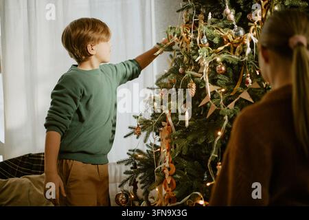 Junge dekoriert zu Hause mit der Familie den Weihnachtsbaum Stockfoto