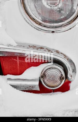 Nahaufnahme eines vintage Autoscheinwerfers, der im Winter mit Schnee bedeckt ist Stockfoto