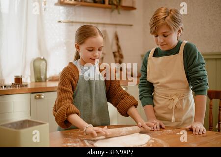 Zwei Kinder kneten gemeinsam in der Küchenstube den Teig Stockfoto