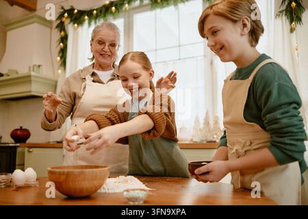 Seniorin backt Gebäck mit Kindern während der Feiertagsvorbereitung Stockfoto