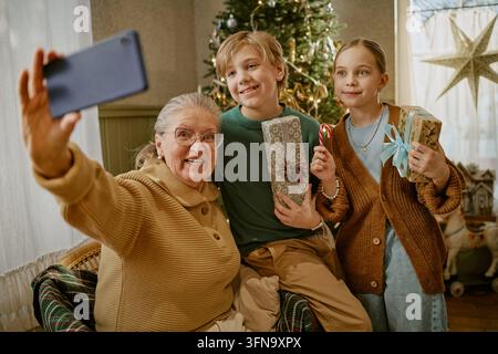 Seniorin macht Selfie mit Enkelkindern an Weihnachten zu Hause Stockfoto
