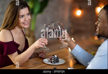 Happy interracial paar mit Gläsern Rotwein mit Datum Im Restaurant Stockfoto