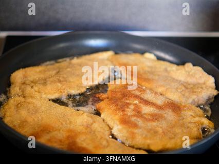 Knusprige panierte Fleischkoteletts braten und brutzeln in einer Pfanne mit Öl Stockfoto