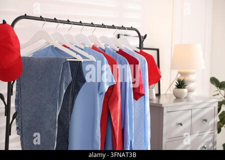 Verschiedene Kleidungsstücke und Baseballkappe hängen an einem Regal im Innenraum, Nahaufnahme. Platz für Text Stockfoto