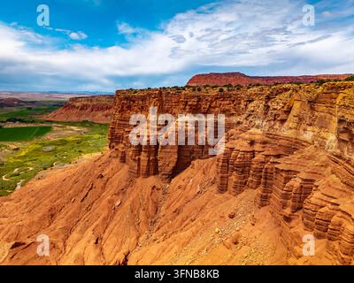 Aufragende rote Sandstein-Badlands und steile Klippen erheben sich schroff über einen gewundenen Flusskorridor in der Nähe des Capitol Reef National Parks in Utah Stockfoto