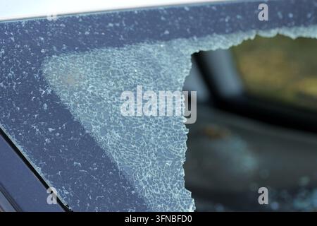 Zersplittertes gehärtetes Auto-Seitenfenster mit Spinnennetz-Rissen und fehlenden Teilen nach dem Aufprall, das Vandalismus, Diebstahl oder Unfall, Fahrzeugschaden, Unsicherheit vermittelt Stockfoto