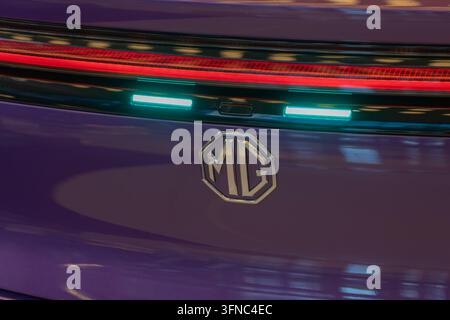 Achtkantiges Automobil-Emblem auf dem Heck eines lila Autos mit beleuchteten Rückleuchten Stockfoto