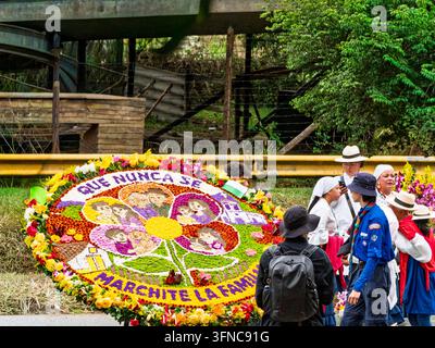 Eine massive runde Blumenauslage aus Silletero mit einem Blumendesign, das Porträts von Familien zeigt, und dem Text Que Nunca Se Marchite La Familia. Stockfoto