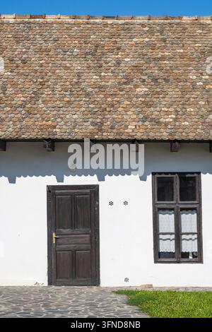 Detail eines alten Bauernhauses mit Ziegeldach, Fenster und Holztür im ethnographischen Dorf Holloko in Ungarn, Europa Stockfoto