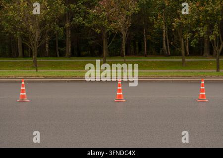 Verkehrskegel auf frischem Asphalt. Straßenbaugrenze, Verkehrsbeschränkung, Baustellenkonzept mit großem Kopierraum Stockfoto