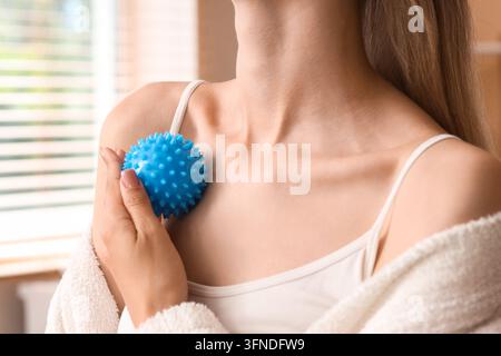 Myofaszien-Release und Muskel Schmerz Linderung, Frau verwendet einen blauen stacheligen Massageball für Triggerpunkt-Therapie und Schulterverspannungs-Recovery zu Hause Stockfoto