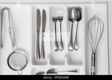 Organisation und Hausmanagement, sauberes Besteckfach mit sortierten Edelstahl-Küchenutensilien und Silberbesteck in einem weißen Schubladenorganizer Stockfoto